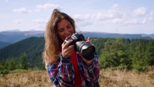 Γυναίκα κρατώντας φωτογραφική μηχανή στα χέρια. Φωτογράφος κοιτάζοντας εικόνες στην κάμερα - Πλάνα, βίντεο