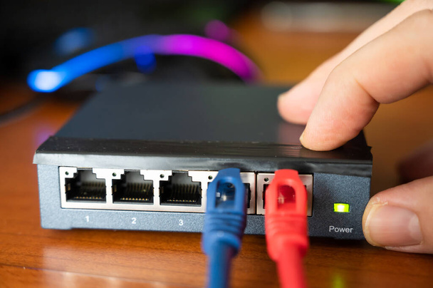 Lähikuva reitittimestä - punainen kaapeli on kytketty sinisen Ethernet-kaapelin viereen. Käsite kaapelointi, internet-verkko, työskentely Internet-verkon. Käyttö ja huolto - Valokuva, kuva