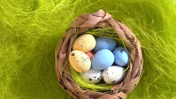 4k video. Yeşil çimen arka planında paskalya renkli yumurtaları olan rotasyon yuvası. Geleneksel bahar kompozisyonu ilkbahar için Paskalya elementleri çiçekler ve yumurtalar. 360 dönmeli Paskalya dekorasyonunun üst görünümü.  - Video, Çekim