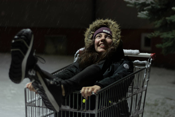 Onnellinen nuori nainen sisällä ostoskorissa talvella lumimyrsky - Valokuva, kuva