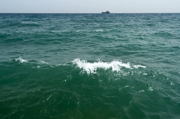 Wavy aquamarine sea water surface, white foam and ship on the horizon - Foto, Imagen