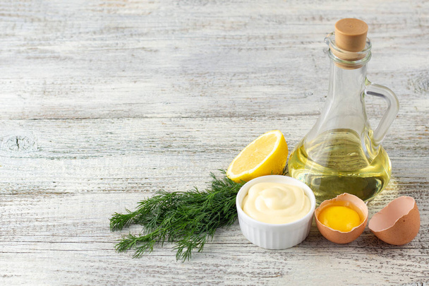 Salsa de mayonesa con ajo, huevo, aceite, limón y hierbas sobre fondo de madera blanca - Foto, Imagen