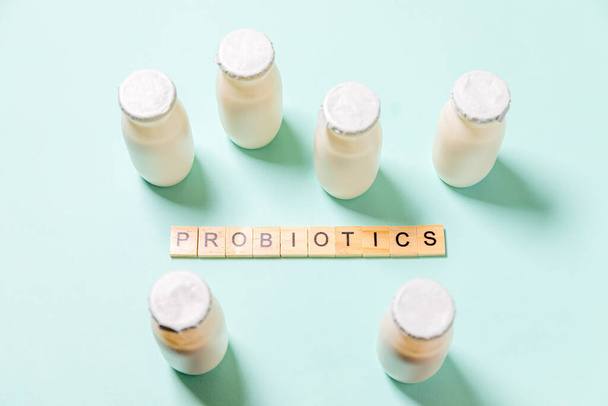 Kis üvegek probiotikumokkal és prebiotikumokkal, kék alapon. Biológiailag aktív adalékanyagokkal történő előállítás. Erjesztés és diéta egészséges étel. Bio joghurt hasznos mikroorganizmusokkal - Fotó, kép