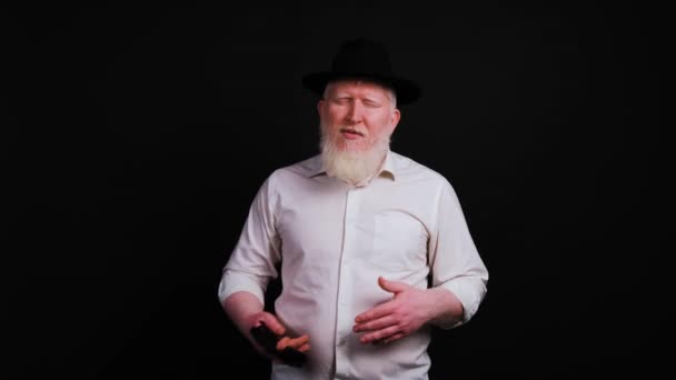 Portret mężczyzny z albinizmem mówiącego przed kamerą na czarnym tle - Materiał filmowy, wideo