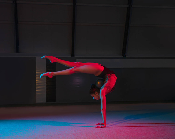 Nuori siro tyttö rytminen voimistelija eristetty tummalla taustalla neon valossa - Valokuva, kuva