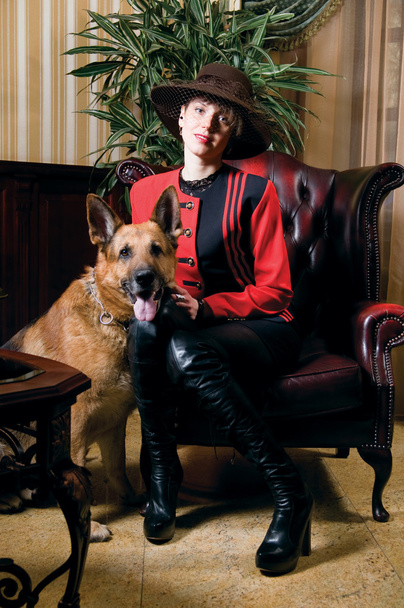 Mujer joven sentada en un sillón de cuero y acariciando al perro
 - Foto, imagen