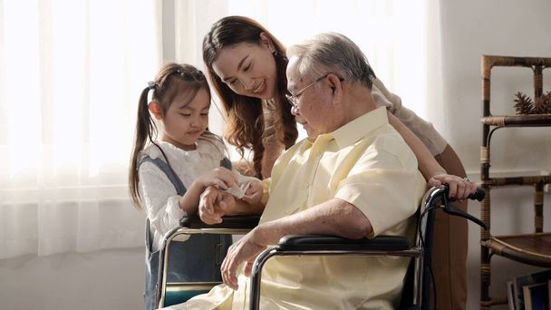 Aziatische Senior man was ziek en zat op een rolstoel. Ouderdom levensstijl en saamhorigheid met familie thuis. - Foto, afbeelding