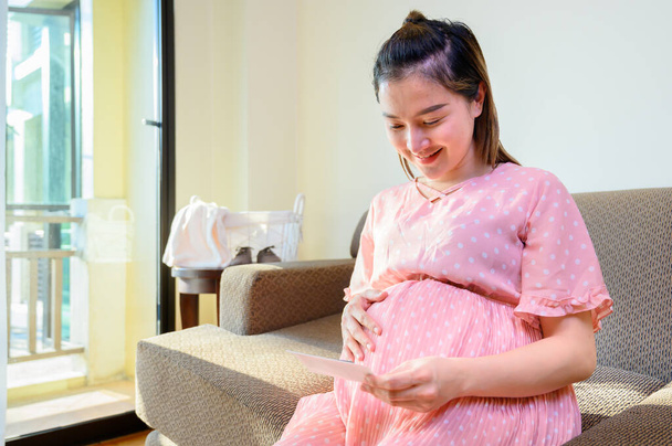 Aasialainen raskaana oleva nainen jää yksin kotiin. Vauvan röntgenkuva raskaudesta. - Valokuva, kuva