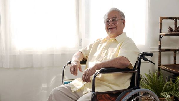 孤独なアジア系の老人は病気で車椅子に座っていた。退職年齢のライフスタイルと一人で家にいる. - 写真・画像