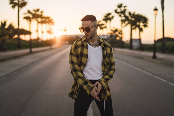 A stylish European man standing in a middle of a road at sunset - Photo, Image