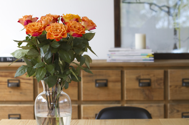 Rosas naranjas en mesa de comedor escena interior
 - Foto, imagen