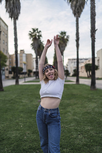 A young pretty Caucasian female posing in a park with a USA flag headband on her head - Foto, Imagen