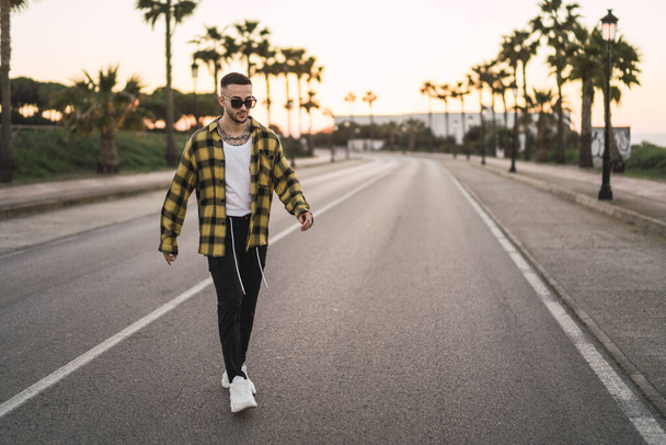 A stylish European man in a plaid shirt walking on a road - 写真・画像