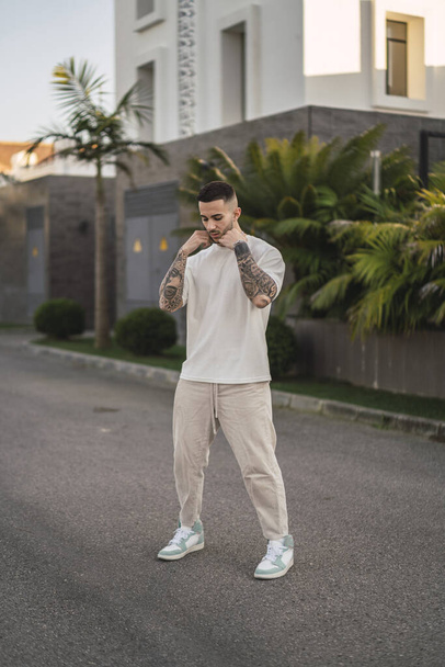 A vertical shot of a tattooed stylish man posing on the street - Photo, Image