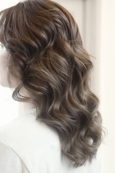 light brown long curly loose hair close up photo in hair salon back view - Photo, Image