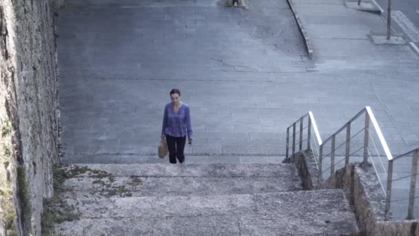 Angolo basso di elegante imprenditore con valigetta elegante a piedi su passi grezzi nella giornata di sole sulla strada della città - Filmati, video