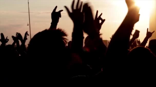 Οπίσθια όψη σιλουέτες των ανθρώπων με τα χέρια επάνω κατά φωτίζεται με μαύρα φώτα σκηνή κατά τη διάρκεια της μουσικής παράστασης - Πλάνα, βίντεο