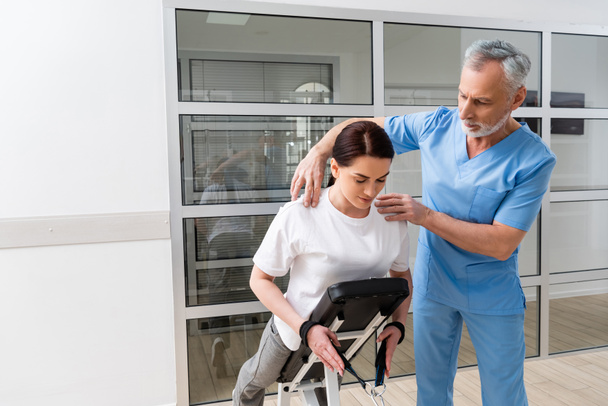 physiothérapeute mature aidant la femme pendant la réadaptation physique - Photo, image