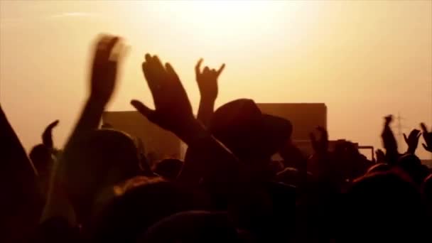 Silhouetten von Menschen mit erhobenen Händen gegen die mit Schwarzlicht beleuchtete Bühne während der Musikdarbietung - Filmmaterial, Video