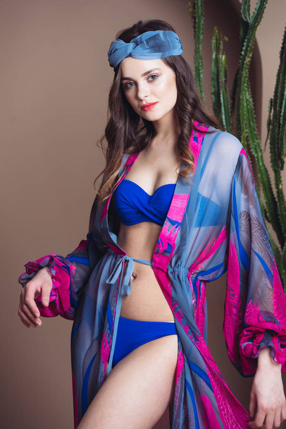 gyönyörű fiatal nő bikini pózol a kék háttér - Fotó, kép