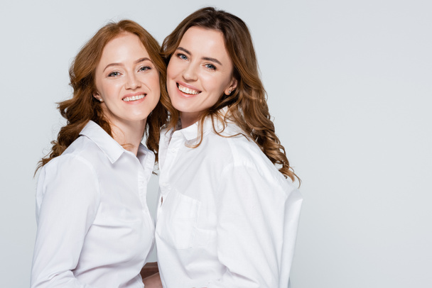 Γυναίκες με άσπρα πουκάμισα που χαμογελούν στην κάμερα απομονωμένες σε γκρι  - Φωτογραφία, εικόνα