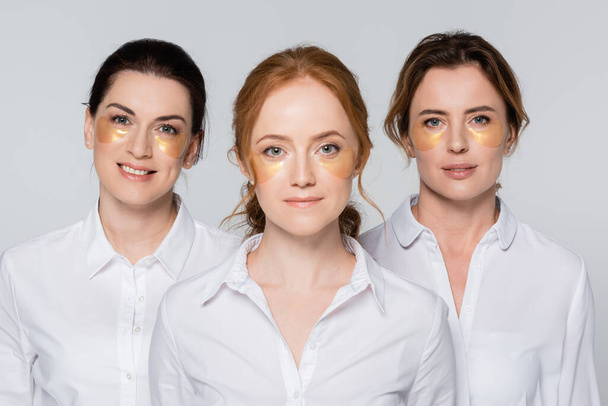 Mulheres adultas com manchas nos olhos sorrindo para a câmera isoladas em cinza  - Foto, Imagem