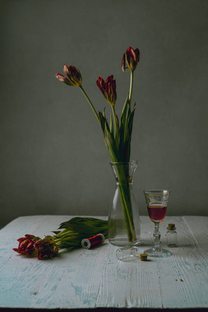 Nature morte avec des tulipes fanées et un verre de vin rouge - Photo, image