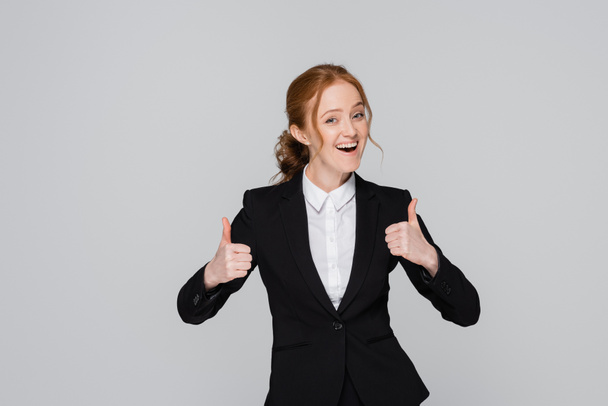 Щаслива бізнес-леді показує великі пальці вгору ізольовані на сірому
  - Фото, зображення