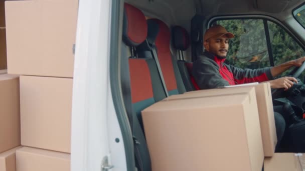 Чоловік доставки перевіряє список замовлень на планшеті, сидячи у фургоні, повній пакунків
 - Кадри, відео