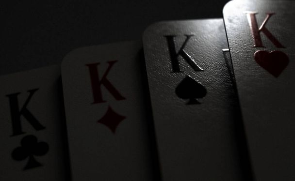 Una vista de cerca de un palo desplegado de cuatro rey del casino jugando a las cartas sobre un fondo tenue iluminado - 3D render - Foto, imagen