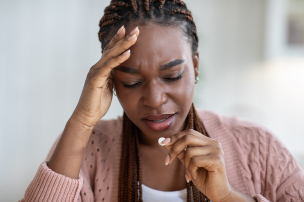 Upset black lady suffering from headache or migraine at home, taking pill - Photo, Image