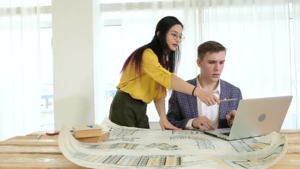 Team of designers work in bright office with large windows brainstorming. on table are detailed drawings that architects carefully study and analyze the technical project. Meeting of the design team - Footage, Video