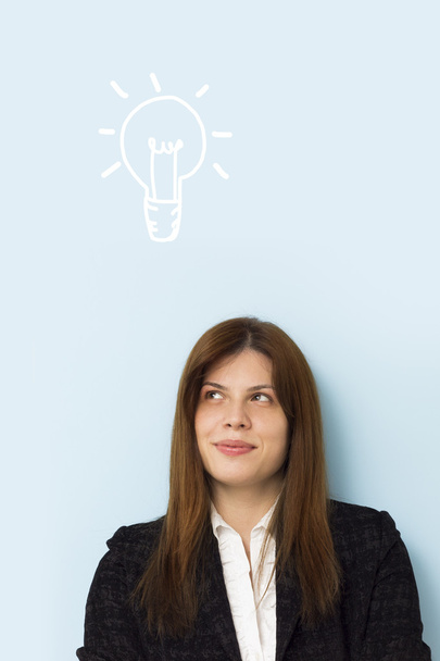 Mulher de negócios bonita sorrindo e pensando em uma ideia brilhante com lâmpada acima de sua cabeça
 - Foto, Imagem