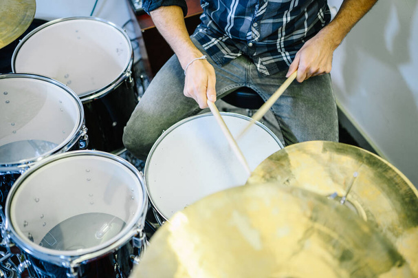 Человек в джинсах и футболке играет на барабанах во время записи. - Фото, изображение