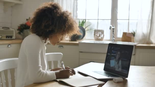 Ciemnoskóra kobieta bierze udział w lekcji online i pisze notatki - Materiał filmowy, wideo