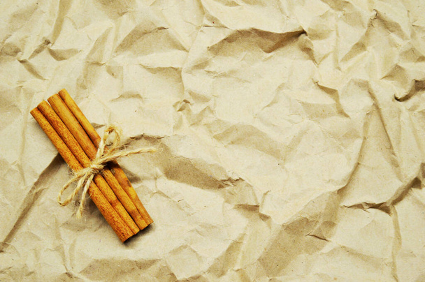 A fahéjrudak egy jutakábellel vannak megkötözve barna papíralapon.. - Fotó, kép