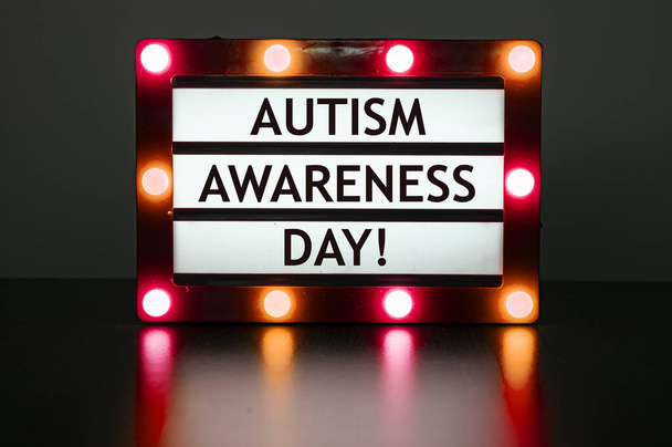 Світлова коробка з червоним світлом зі словами - День обізнаності аутизму! Всесвітній день обізнаності про автизм - всесвітній день, що відзначається щороку 2 квітня.. - Фото, зображення
