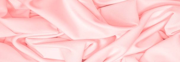 The fabric is silk of a pale red color. Texture. Background. Pattern. Silk fabric has a shiny sheen and characteristic small folds that run horizontally. She lies down in soft folds - Zdjęcie, obraz