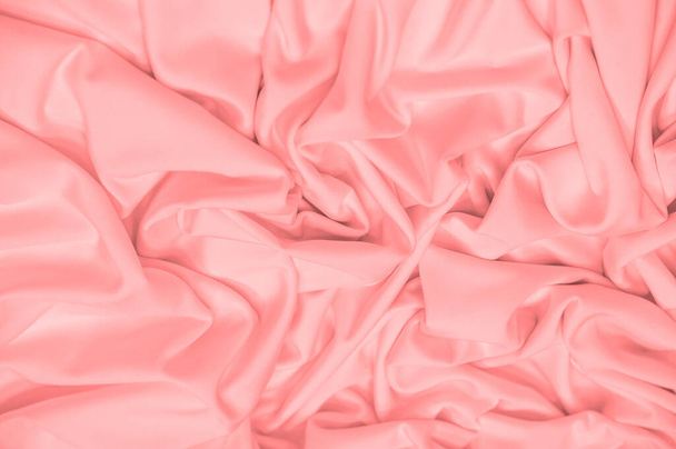 The fabric is silk of a pale red color. Texture. Background. Pattern. Silk fabric has a shiny sheen and characteristic small folds that run horizontally. She lies down in soft folds - Photo, image