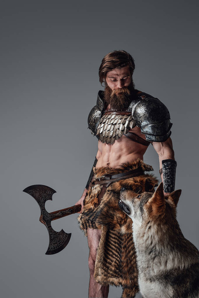 Mítico bárbaro nórdico armado con hacha posando con lobo salvaje - Foto, Imagen