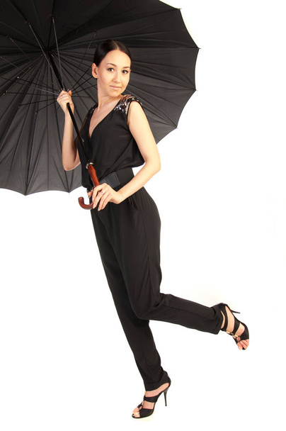 Studio zdjęcia modelki. Moda bardzo fajna kobieta trzyma czarny parasol w jesienny dzień na białym tle w czarnym garniturze - Zdjęcie, obraz
