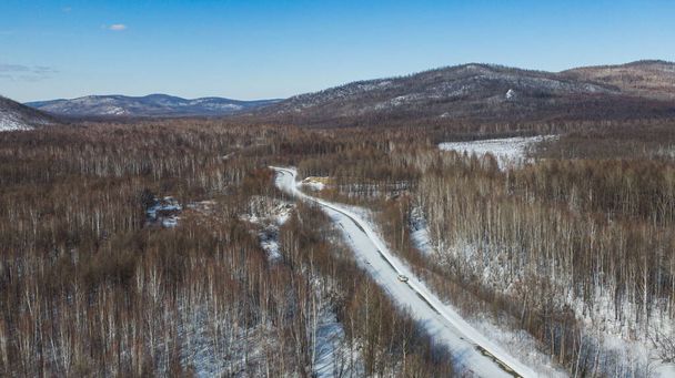 Letecký pohled na řeku a taigské lesy a silnici v zimě - jaro. Abstraktní krajina severní přírody s dronem. - Fotografie, Obrázek