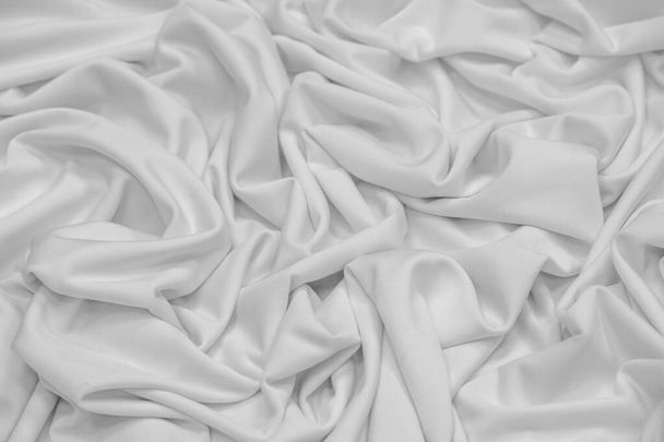 白い絹の生地。テクスチャ。背景。パターンだ。Duponiシルク生地は光沢のある光沢があり、水平方向に走る特徴的な小さな折り目を持っています。彼女は柔らかい折り目に横たわっている - 写真・画像