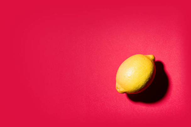 Isolated lemon projecting shadow on red background - Photo, Image