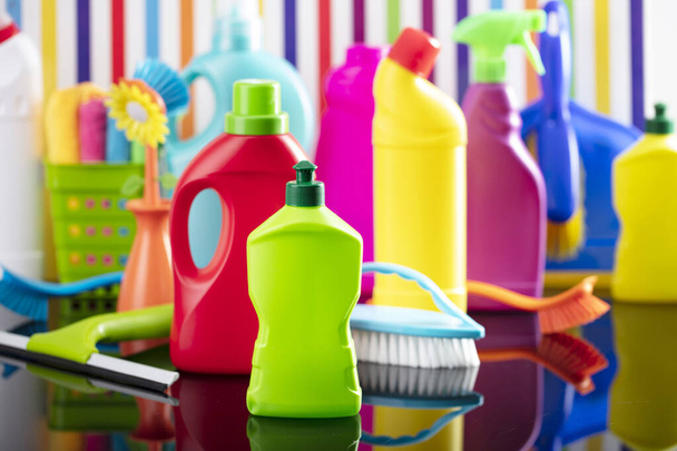 Tavaszi ház és irodai takarítás téma. Színes készlet palack, klinikai folyadékok és színes tisztító készlet a háttérben formájában színes csíkok. - Fotó, kép