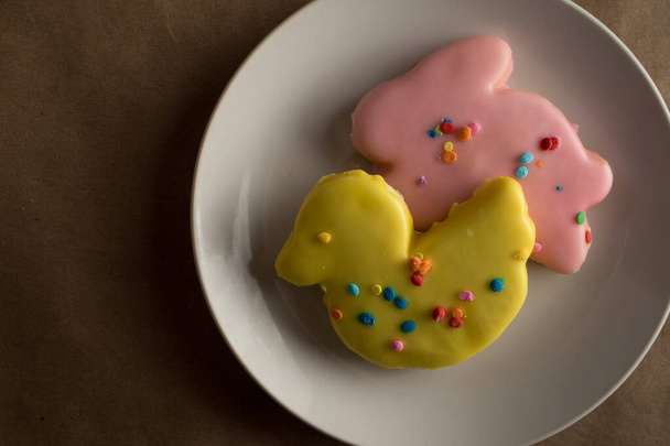 Fiesta tradicional galletas de azúcar de Pascua esmeriladas en colores de primavera en un plato. Las galletas están en formas de conejo y pato con pato amarillo en primer plano. - Foto, imagen