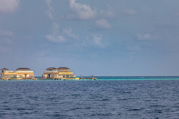 Панорамный пейзаж Мальдивского пляжа. Фешенебельная панорама, роскошный водный курорт с деревянным пиром или причалом. Предыстория для концепции летнего отдыха и путешествий. - Фото, изображение