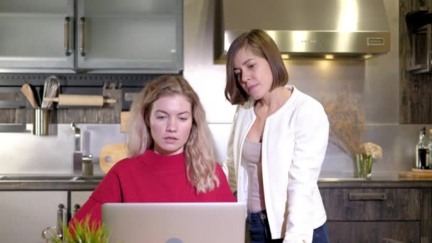 Twee meisjes werken op afstand samen. Zakelijke vrouwen bespreken werk project op de computer in keuken huis. Uitwisseling van ideeën en brainstormen. Bespreking en beslissing. team van professionals die werken - Video