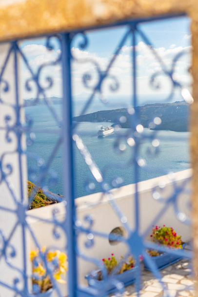 Wyspa Santorini, Grecja. Niesamowita biała architektura, błękitne niebo i relaksujący letni nastrój. Wibracje, podróże i wakacje. Piękna wakacyjna sceneria. Niebieski płot z widokiem na morze - Zdjęcie, obraz