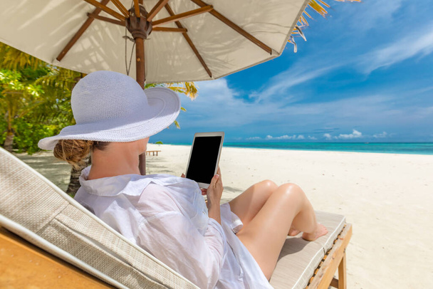 bela mulher de chapéu branco segurando tablet na praia - Foto, Imagem